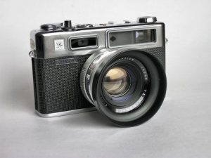 An original Yashica Electro 35 from 1966 (with lens hood). Notice the absence of the "G" before Yashica, absence of the word "COLOR" on the lens, and the all metal film advance lever.