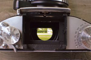 The viewfinder has it's own ground glass, so when you remove it, you look directly into the mirror box.