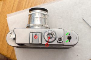 Only remove the two black screws with the green checks. Do not remove the screw in the accessory post or the large screw inside of the film speed shaft.
