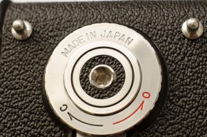 The last of the Yashica-Ds had a black plastic locking knob and some were made in Hong Kong.  My example still has the metal chrome knob with "Made in Japan" engraved into the metal.
